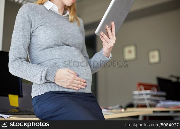 pregnancy, business, work and technology concept - close up of pregnant businesswoman with tablet pc computer at office. pregnant businesswoman with tablet pc at office. pregnant businesswoman with tablet pc at office