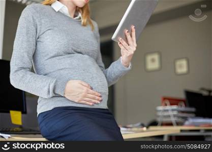 pregnancy, business, work and technology concept - close up of pregnant businesswoman with tablet pc computer at office. pregnant businesswoman with tablet pc at office. pregnant businesswoman with tablet pc at office