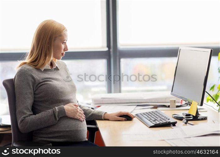 pregnancy, business, work and technology concept - pregnant businesswoman with computer sitting at office table. pregnant businesswoman with computer at office