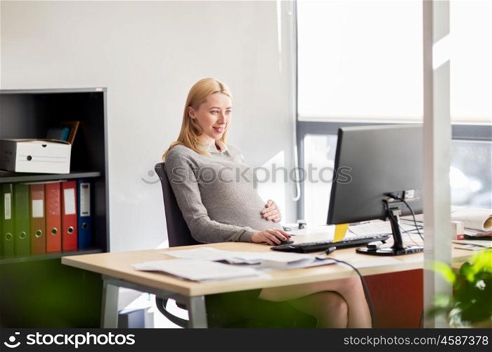 pregnancy, business, work and technology concept - smiling pregnant businesswoman with computer at office table