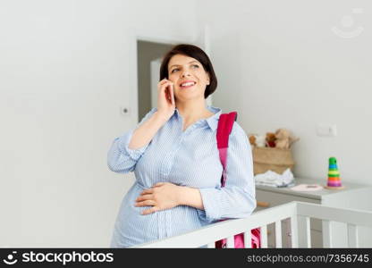 pregnancy, communication and nursery concept - happy pregnant middle-aged woman with bag for maternity hospital and calling on smartphone at home. pregnant woman with hospital bag and calling