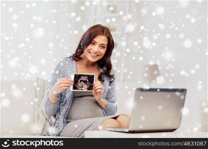 pregnancy, communication, winter, people and technology concept - happy pregnant woman with laptop computer having video call and showing ultrasound image at home over snow