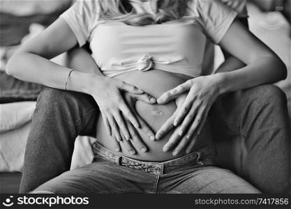 pregnancy concept childbirth and love / man and woman, big belly, hands in the shape of a heart, symbol of pregnancy and love