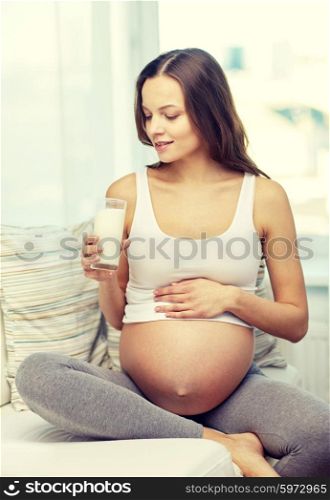 pregnancy, drinks, healthy eating, people and expectation concept - happy pregnant woman drinking milk from glass at home