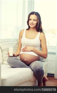 pregnancy, drinks, healthy eating, people and expectation concept - happy pregnant woman drinking milk from glass at home