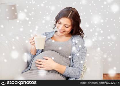pregnancy, drinks, people, winter and expectation concept - happy pregnant woman with cup drinking tea at home over snow