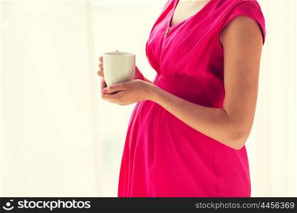 pregnancy, drinks, rest, people and expectation concept - close up of pregnant woman with cup drinking tea at home