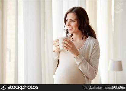 pregnancy, drinks, rest, people and expectation concept - happy pregnant woman with cup drinking tea at home