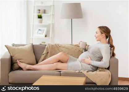 pregnancy, drinks, rest, people and expectation concept - happy pregnant woman with cup drinking tea at home. happy pregnant woman with cup drinking tea at home