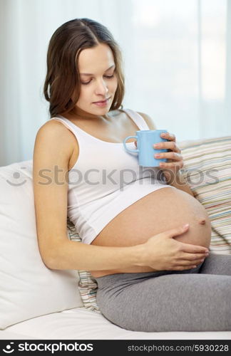 pregnancy, drinks, rest, people and expectation concept - happy pregnant woman with cup drinking tea at home