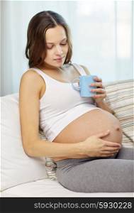 pregnancy, drinks, rest, people and expectation concept - happy pregnant woman with cup drinking tea at home