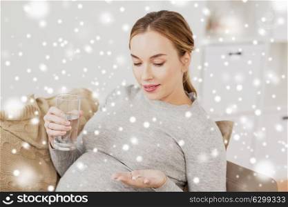 pregnancy, drinks, rest, people and expectation concept - happy pregnant woman with water and pills at home over snow. happy pregnant woman with water and pills at home