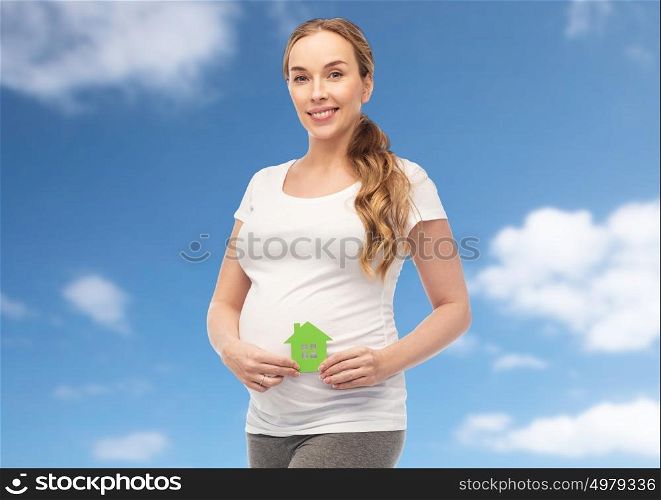 pregnancy, ecology, people and housing concept - happy pregnant woman with green house over blue sky and clouds background. happy pregnant woman with green house