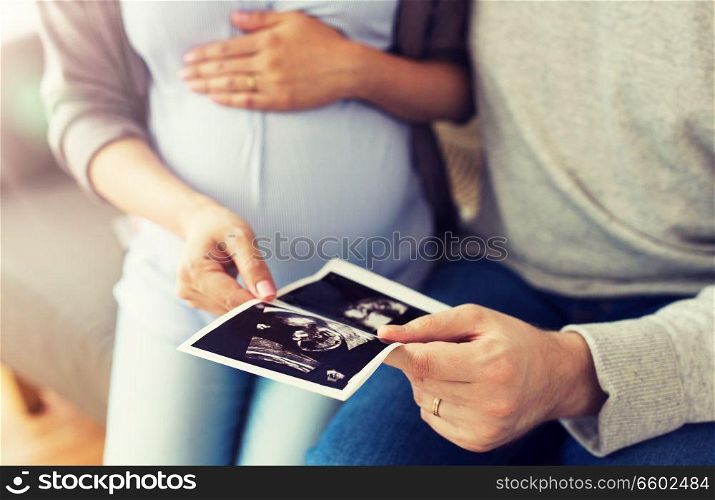 pregnancy, family and people concept - close up of man with his pregnant wife looking at baby ultrasound images at home. close up of couple with baby ultrasound images