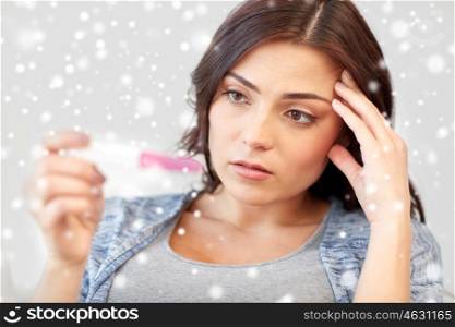 pregnancy, fertility, infertility, maternity and people concept - sad unhappy woman looking at pregnancy test at home over snow