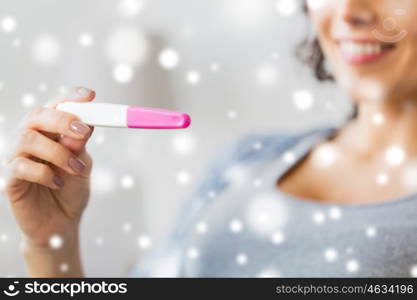 pregnancy, fertility, maternity and people concept - close up of happy smiling woman with home pregnancy test over snow