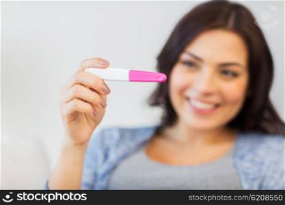 pregnancy, fertility, maternity and people concept - close up of happy smiling woman looking at pregnancy test at home