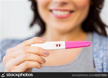 pregnancy, fertility, maternity and people concept - close up of happy woman with positive home pregnancy test