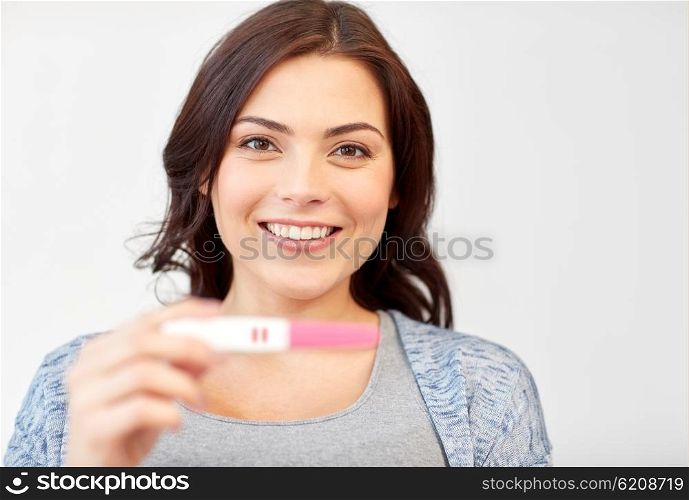 pregnancy, fertility, maternity and people concept - happy smiling woman holding and showing positive home pregnancy test