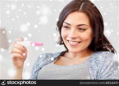 pregnancy, fertility, maternity and people concept - happy smiling woman looking at pregnancy test at home over snow