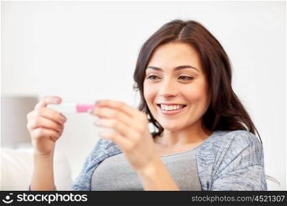pregnancy, fertility, maternity and people concept - happy smiling woman looking at pregnancy test at home