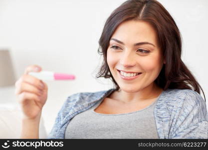 pregnancy, fertility, maternity and people concept - happy smiling woman looking at pregnancy test at home