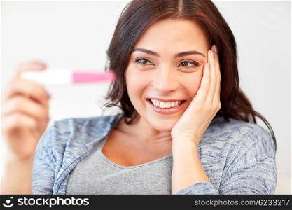 pregnancy, fertility, maternity, emotions and people concept - happy smiling woman looking at pregnancy test at home