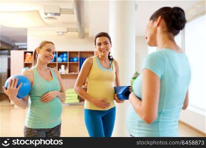 pregnancy, fitness and healthy lifestyle concept - group of happy pregnant women with sports equipment talking in gym. pregnant women with sports equipment in gym