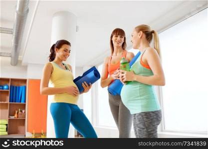 pregnancy, fitness and healthy lifestyle concept - group of happy pregnant women with sports equipment talking in gym. pregnant women with sports equipment in gym