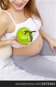 pregnancy, food, healthy eating, people and expectation concept - close up of happy pregnant woman eating green apple at home