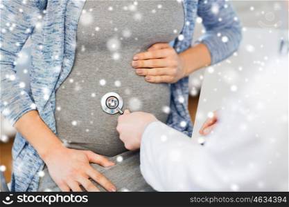 pregnancy, gynecology, medicine, health care and people concept - close up of gynecologist doctor with stethoscope listening to pregnant woman baby heartbeat at hospital over snow