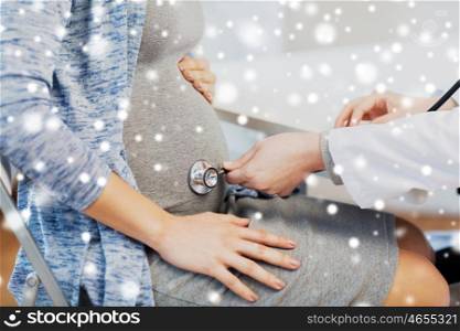 pregnancy, gynecology, medicine, healthcare and people concept - close up of obstetrician doctor with stethoscope listening to pregnant woman baby heartbeat at hospital over snow
