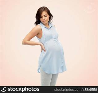 pregnancy, health, people and expectation concept - pregnant woman in bed touching her back and suffering from backache over beige background