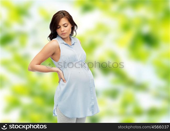 pregnancy, health, people and expectation concept - pregnant woman touching her back and suffering from backache over green natural background