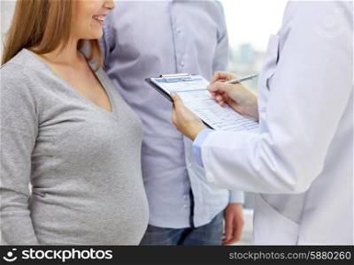 pregnancy, healthcare, people and medicine concept - close up of happy pregnant woman, man and doctor with clipboard at medical appointment in hospital
