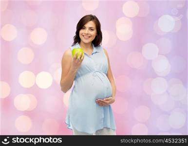 pregnancy, healthy eating, food and people concept - happy pregnant woman holding green apple over rose quartz and serenity holidays lights background