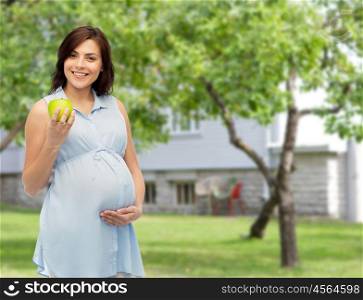 pregnancy, healthy eating, food and people concept - happy pregnant woman holding green apple over summer garden and house background