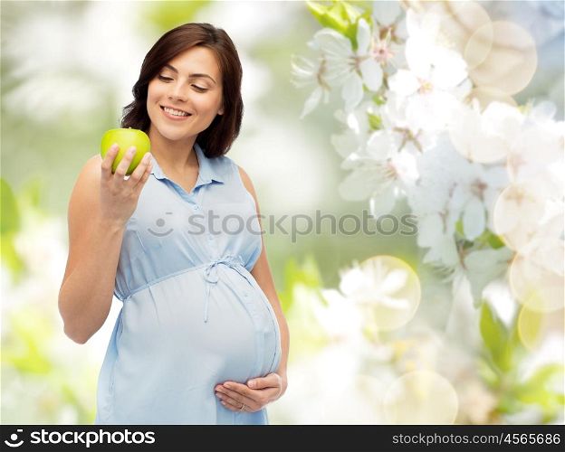 pregnancy, healthy eating, food and people concept - happy pregnant woman holding green apple over natural spring cherry blossom background