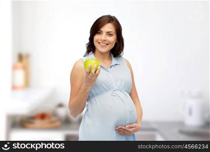 pregnancy, healthy eating, food and people concept - happy pregnant woman holding green apple over home kitchen room background