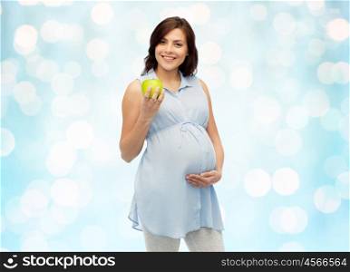 pregnancy, healthy eating, food and people concept - happy pregnant woman holding green apple over blue holidays lights background