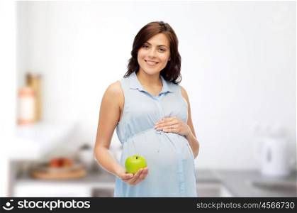 pregnancy, healthy eating, food and people concept - happy pregnant woman holding green apple over kitchen background