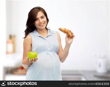pregnancy, healthy eating, junk food and people concept - happy pregnant woman choosing between green apple and croissant over home kitchen room background