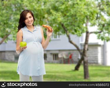 pregnancy, healthy eating, junk food and people concept - happy pregnant woman choosing between green apple and croissant over summer garden and house background