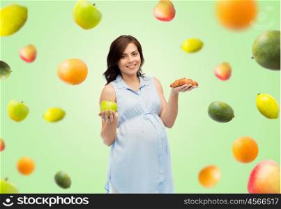 pregnancy, healthy eating, junk food and people concept - happy pregnant woman choosing between green apple and croissant over green natural background with fruits