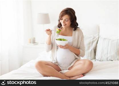 pregnancy, healthy food and people concept - happy pregnant woman eating vegetable salad for breakfast at home