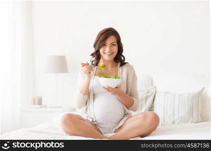 pregnancy, healthy food and people concept - happy pregnant woman eating vegetable salad for breakfast at home