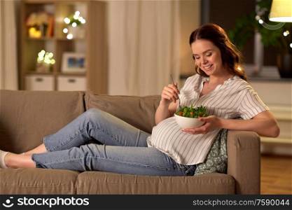 pregnancy, healthy food and people concept - happy smiling pregnant woman eating vegetable salad at home. happy smiling pregnant woman eating salad at home