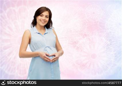 pregnancy, love, people and expectation concept - happy pregnant woman making heart gesture on belly over rose quartz and serenity pattern background