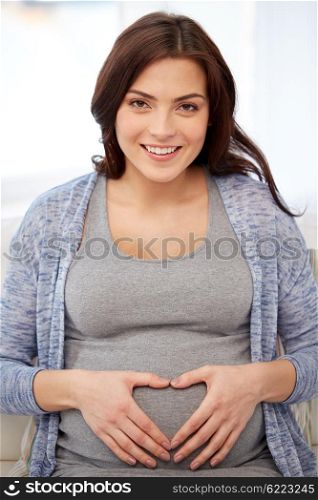 pregnancy, love, people and expectation concept - happy pregnant woman making heart gesture at home