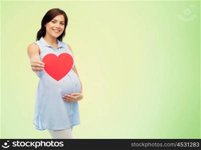 pregnancy, love, people and expectation concept - happy pregnant woman with red heart shape touching her belly over green natural background